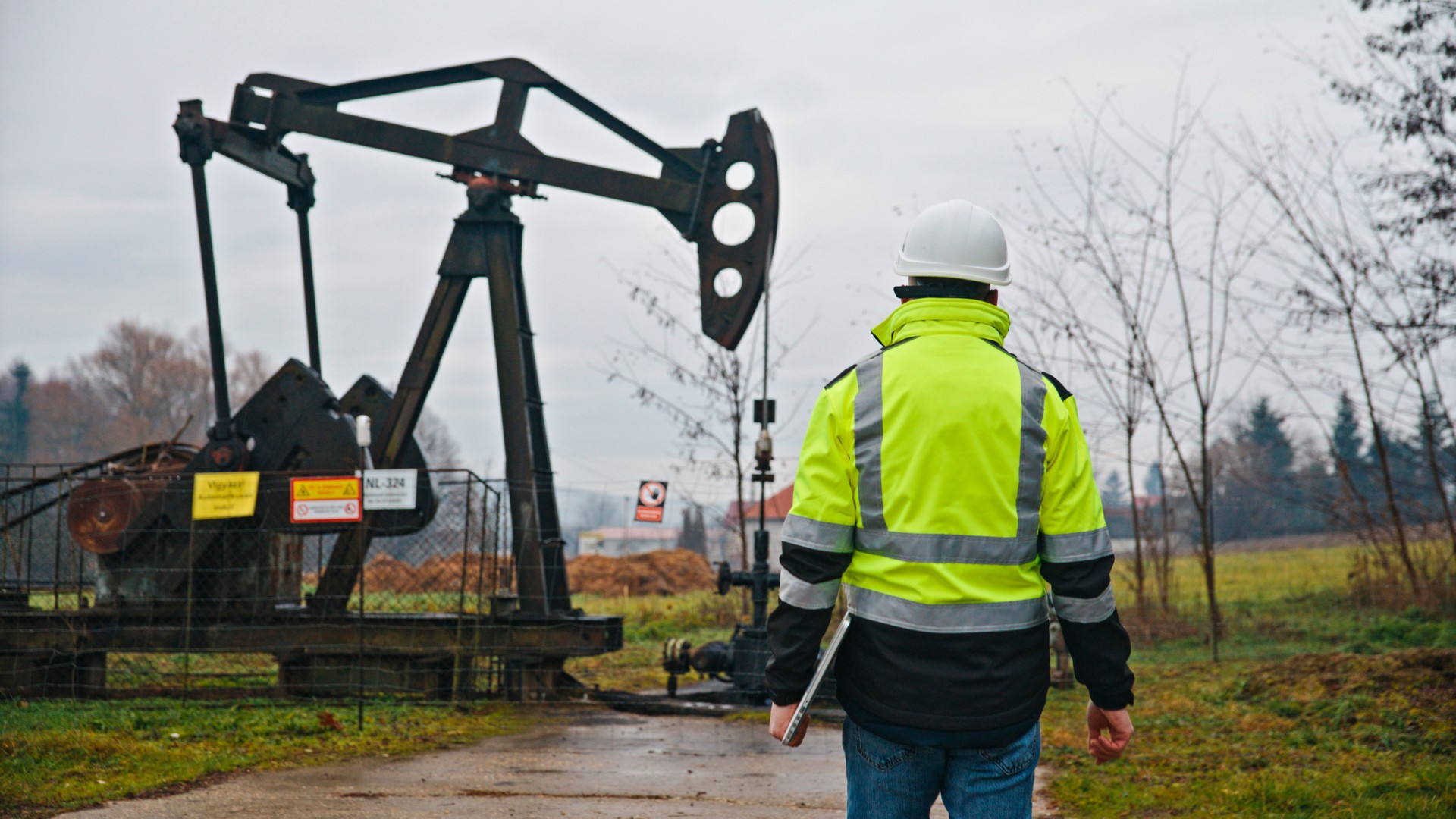 Engineer Inspecting Oil Pump in Safety Gear